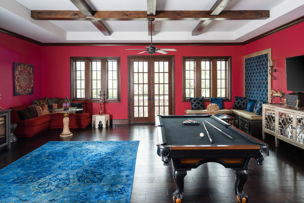 Photo of a mid-sized mediterranean enclosed family room in Houston with a game room, red walls, dark hardwood floors, a wall-mounted tv and brown floor.