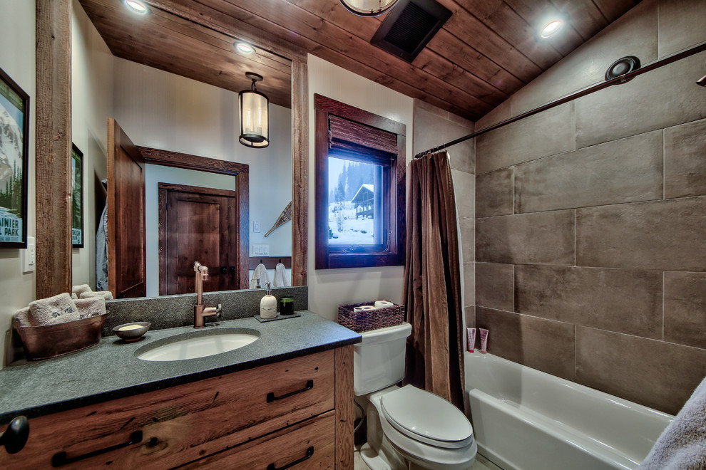 This is an example of a mid-sized country 3/4 bathroom in Vancouver with flat-panel cabinets, light wood cabinets, a shower/bathtub combo, a one-piece toilet, brown tile, porcelain tile, beige walls, concrete floors, a drop-in sink and concrete benchtops.