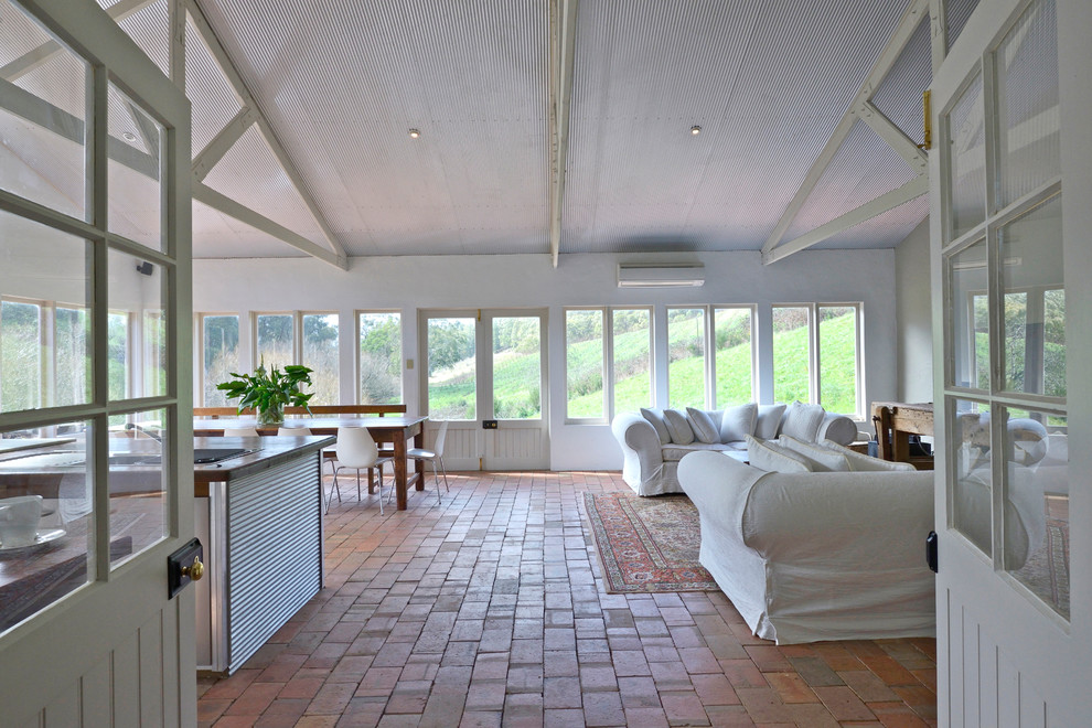 Country open concept living room in Adelaide with white walls and brick floors.