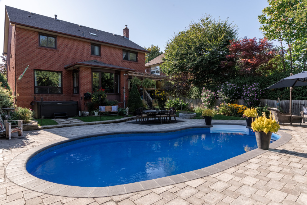 Inspiration for a mid-sized modern backyard kidney-shaped pool in Toronto with with a pool and concrete pavers.