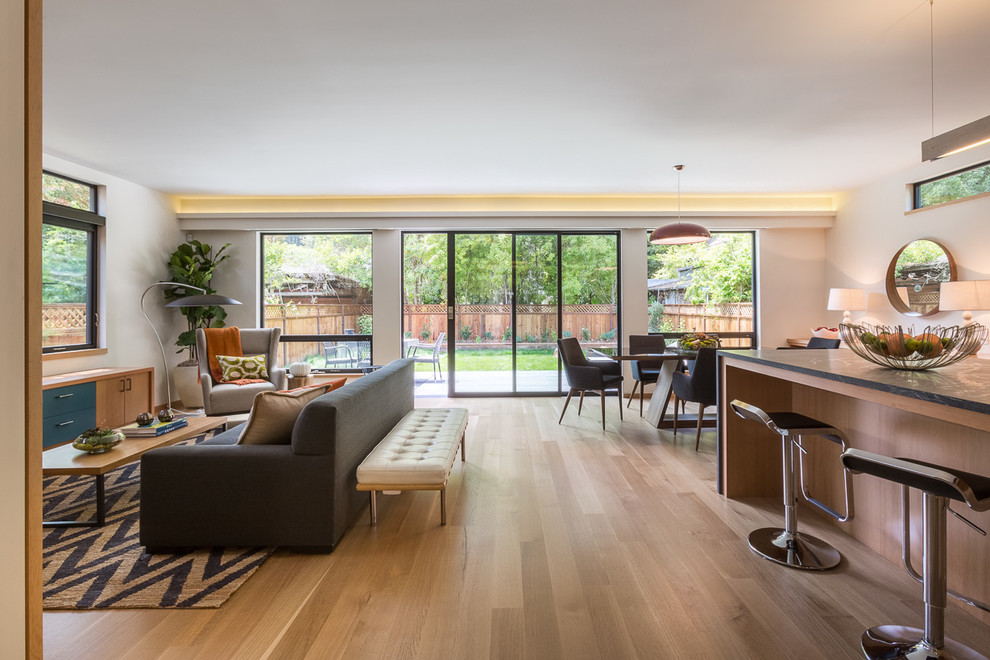 Photo of an expansive contemporary open concept family room in San Francisco with white walls, light hardwood floors, a standard fireplace, a metal fireplace surround and no tv.
