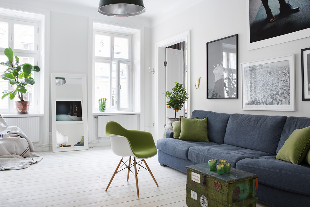 Photo of a large scandinavian open concept living room in Stockholm with white walls, painted wood floors, no fireplace and no tv.