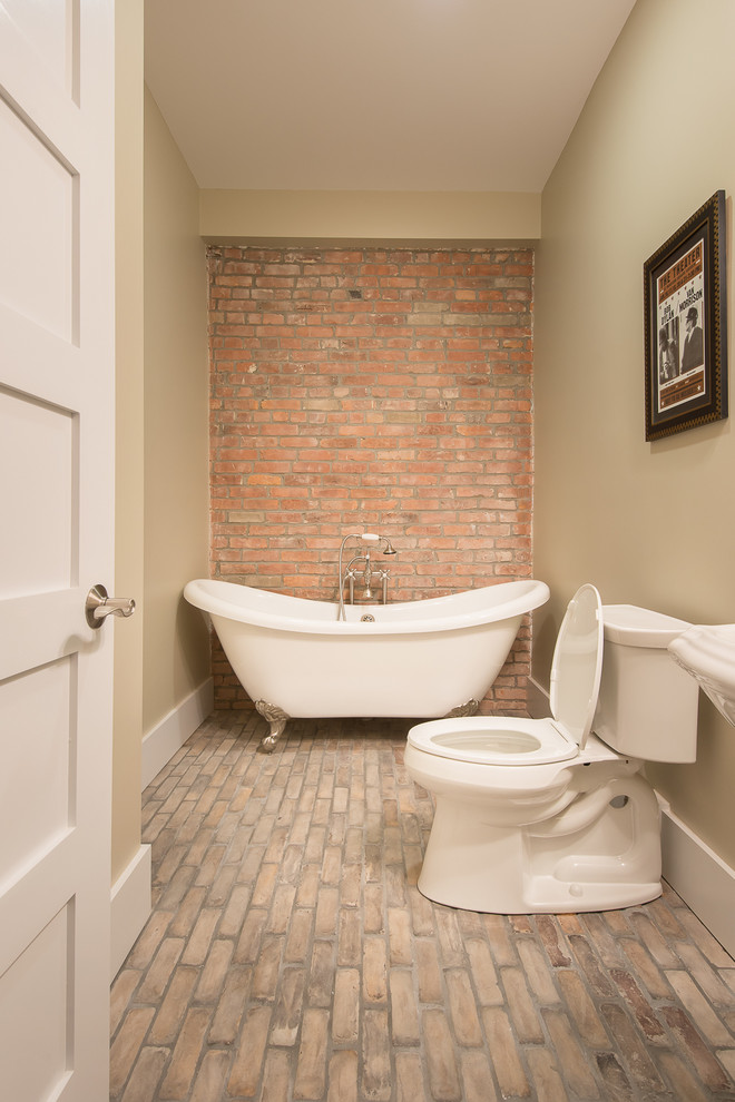 Photo of a mid-sized transitional 3/4 bathroom in Boston with a pedestal sink, a claw-foot tub, a two-piece toilet, beige walls and brick floors.