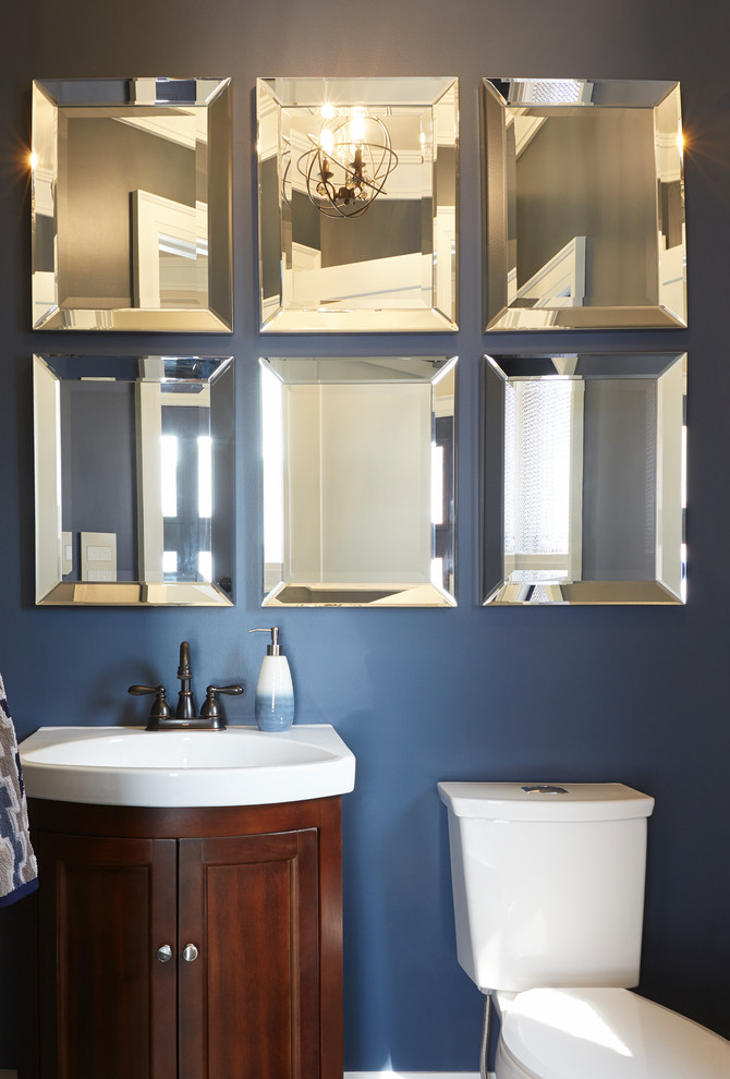 Inspiration for a small contemporary powder room in Toronto with furniture-like cabinets, medium wood cabinets, a two-piece toilet, blue walls, porcelain floors, an integrated sink, solid surface benchtops and grey floor.