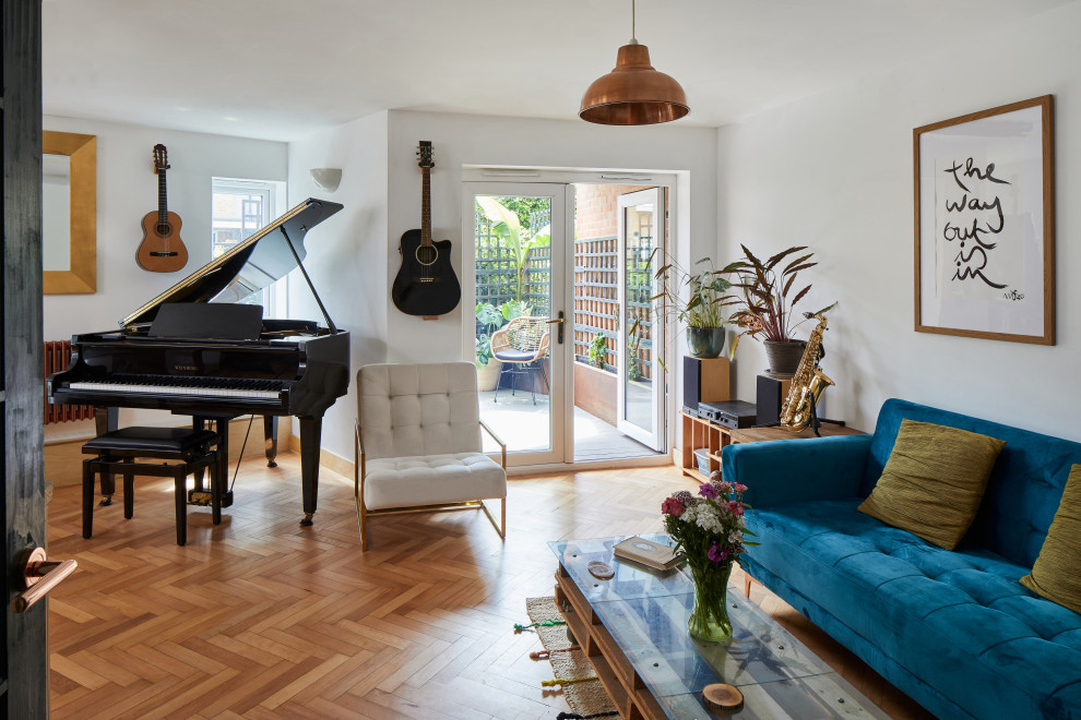 На фото: маленькая изолированная гостиная комната в стиле модернизм с музыкальной комнатой, белыми стенами и светлым паркетным полом без камина для на участке и в саду с