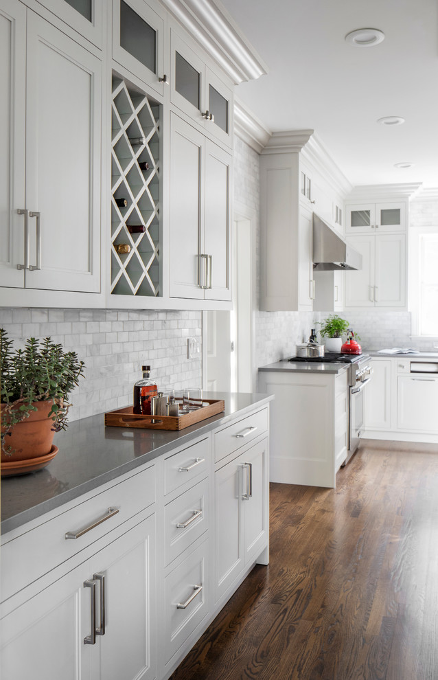 Traditional u-shaped separate kitchen in New York with an undermount sink, beaded inset cabinets, white cabinets, grey splashback, subway tile splashback, stainless steel appliances, medium hardwood floors, with island and brown floor.