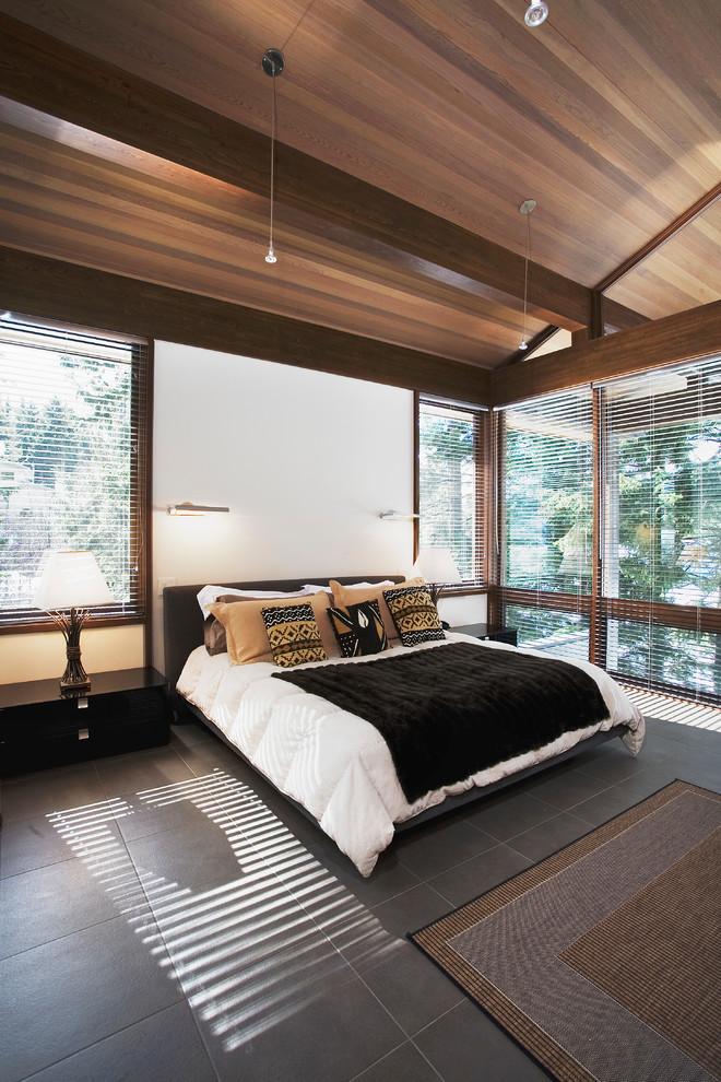 Large contemporary master bedroom in Vancouver with white walls and slate floors.