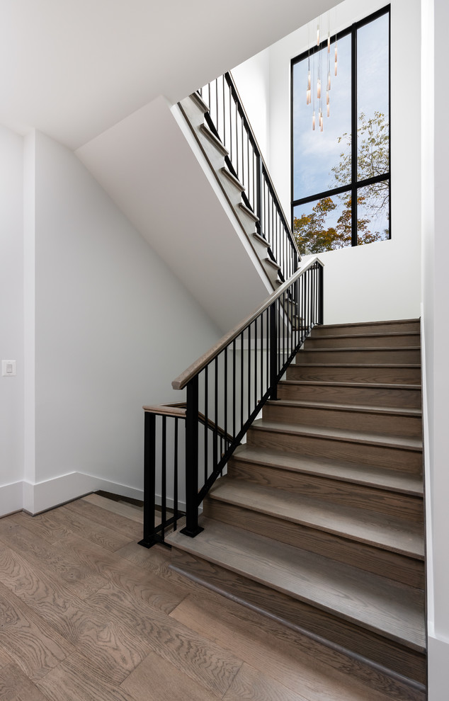 Large modern wood u-shaped staircase in DC Metro with wood risers and mixed railing.