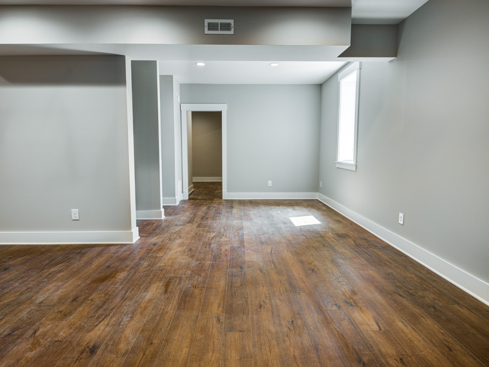 Inspiration for a mid-sized arts and crafts look-out basement in Indianapolis with grey walls and dark hardwood floors.