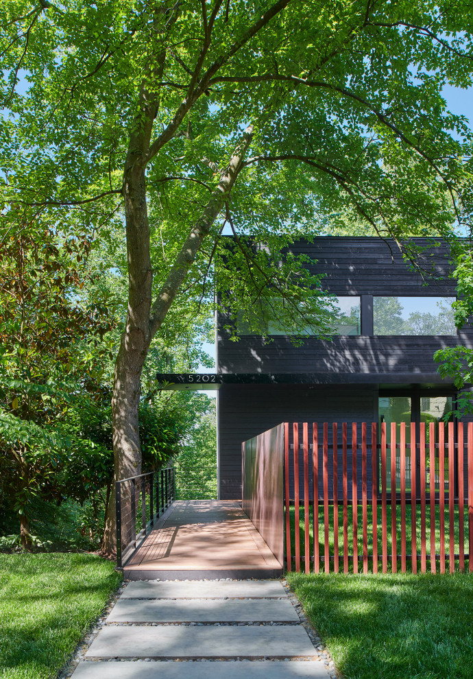 Mid-sized modern three-storey black house exterior in Other with wood siding.