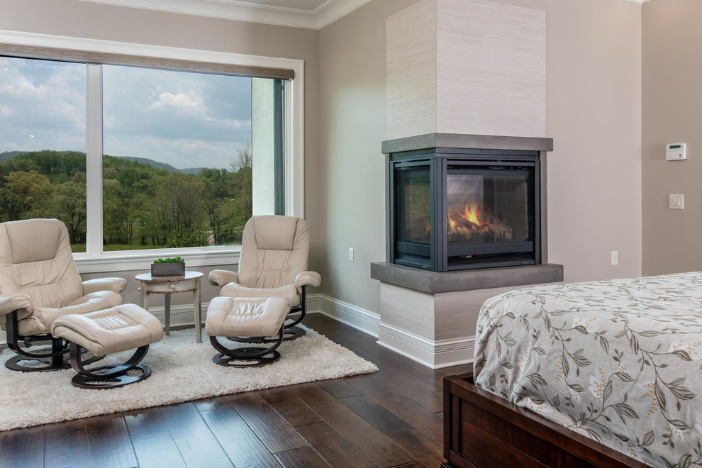 Inspiration for a large transitional master bedroom in Other with beige walls, dark hardwood floors, a corner fireplace, a concrete fireplace surround and brown floor.