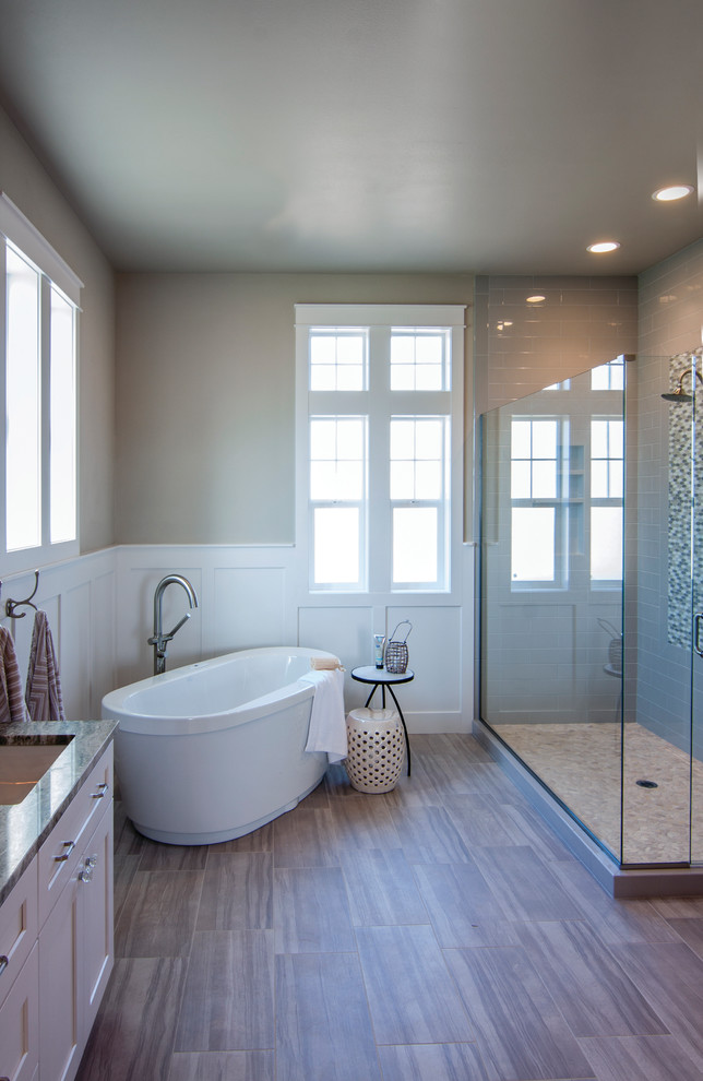 This is an example of a large arts and crafts master bathroom in Seattle with shaker cabinets, white cabinets, a freestanding tub, a corner shower, a two-piece toilet, gray tile, cement tile, grey walls, ceramic floors, an undermount sink and engineered quartz benchtops.