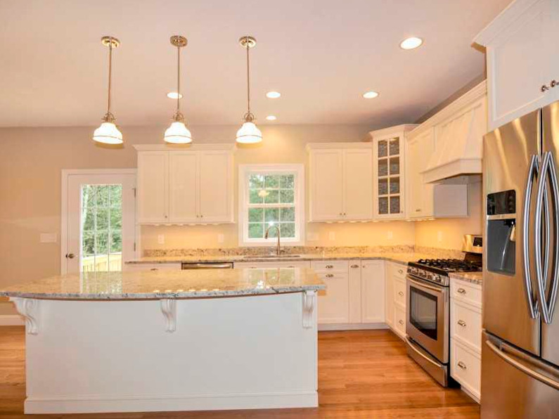Design ideas for a mid-sized transitional l-shaped eat-in kitchen in Providence with a single-bowl sink, shaker cabinets, white cabinets, granite benchtops, white splashback, stone slab splashback, stainless steel appliances, medium hardwood floors and with island.