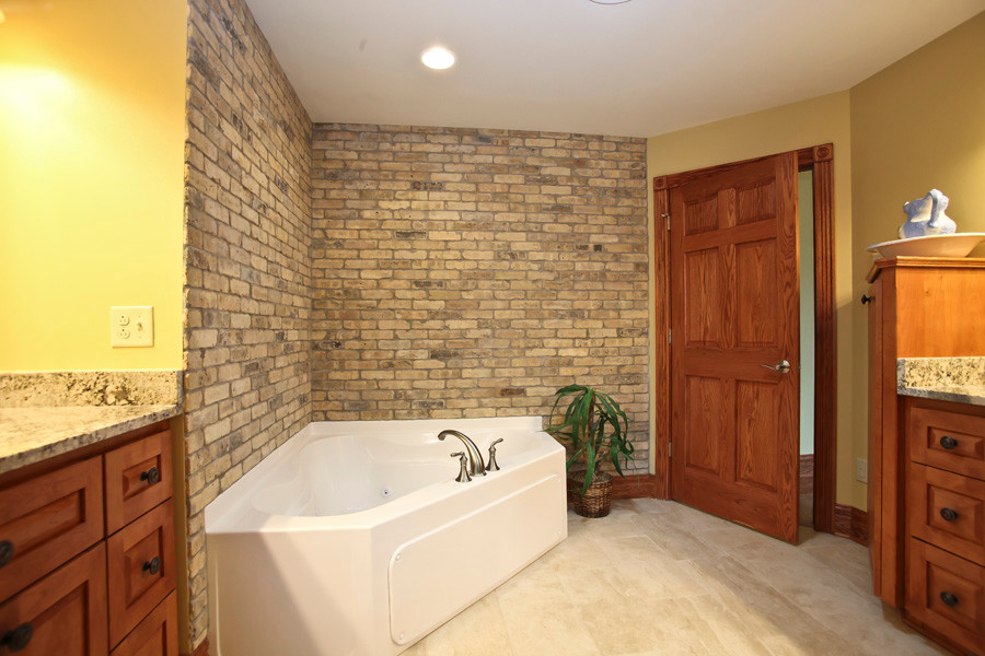 Inspiration for a large rustic master beige tile and ceramic tile ceramic tile corner bathtub remodel in Milwaukee with a console sink, shaker cabinets, medium tone wood cabinets, granite countertops, a two-piece toilet and yellow walls