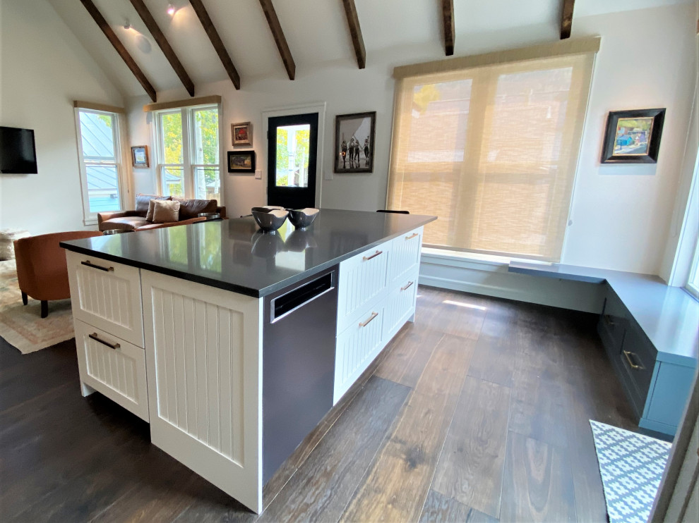 Medium sized contemporary l-shaped open plan kitchen in Other with a belfast sink, recessed-panel cabinets, white cabinets, white splashback, integrated appliances, dark hardwood flooring, an island, brown floors and a vaulted ceiling.