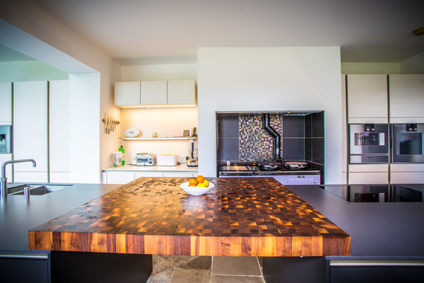 Large contemporary galley kitchen/diner in Hampshire with a submerged sink, flat-panel cabinets, grey cabinets, engineered stone countertops, stainless steel appliances, travertine flooring and an island.