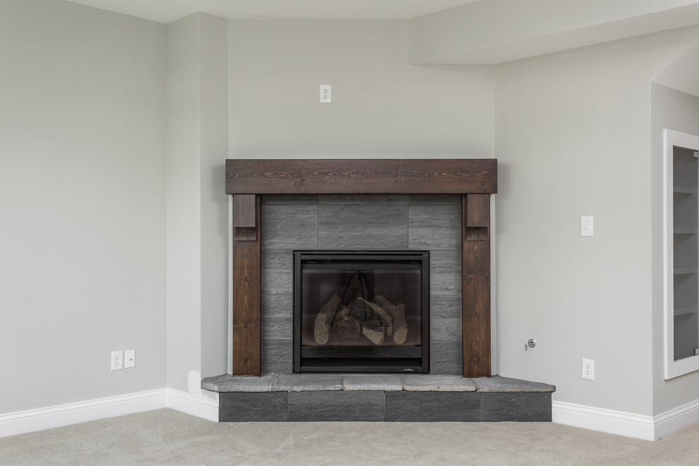 Inspiration for a large arts and crafts look-out basement in Indianapolis with grey walls, carpet, a corner fireplace and a tile fireplace surround.