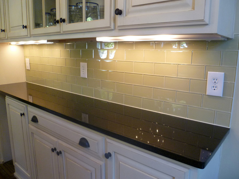 Kitchen - transitional medium tone wood floor kitchen idea with flat-panel cabinets, white cabinets, solid surface countertops, green backsplash, glass tile backsplash and stainless steel appliances