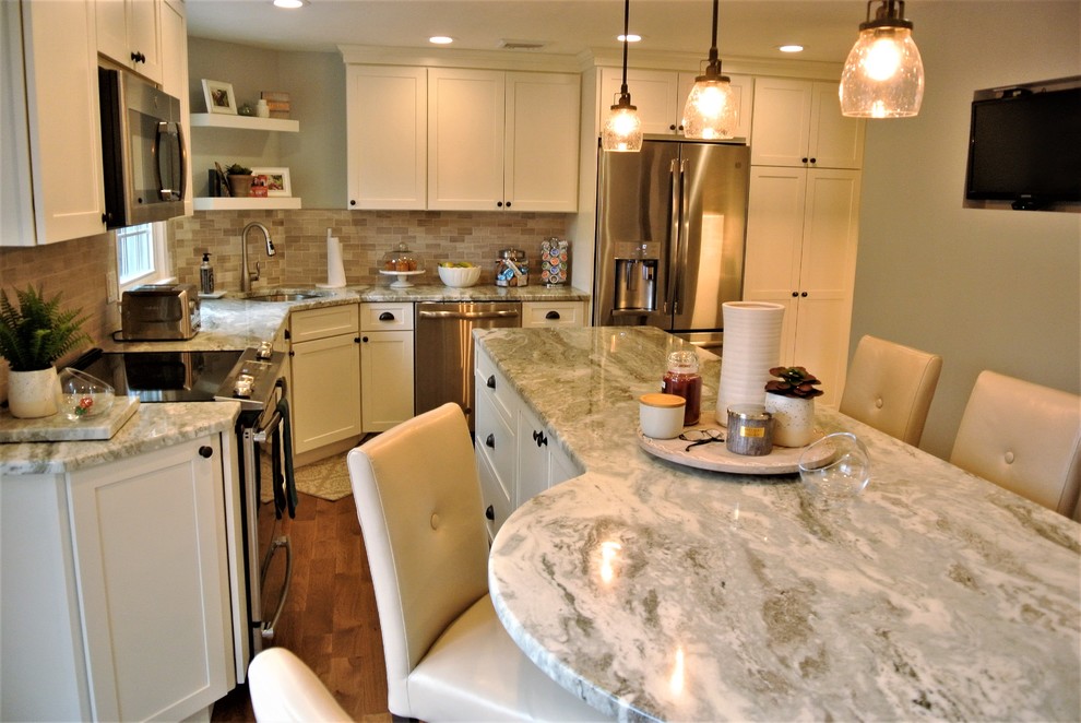 Inspiration for a transitional l-shaped medium tone wood floor kitchen remodel in Boston with an undermount sink, shaker cabinets, white cabinets, granite countertops, beige backsplash, subway tile backsplash, stainless steel appliances and an island