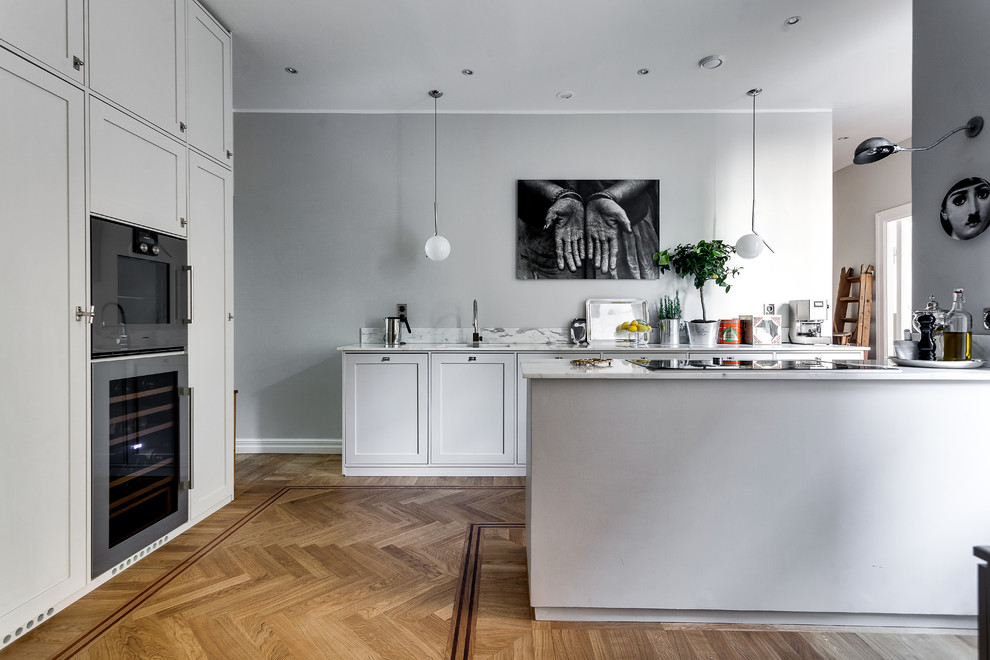 Design ideas for a mid-sized scandinavian galley kitchen in Stockholm with an undermount sink, shaker cabinets, grey cabinets, marble benchtops, stainless steel appliances, light hardwood floors and no island.
