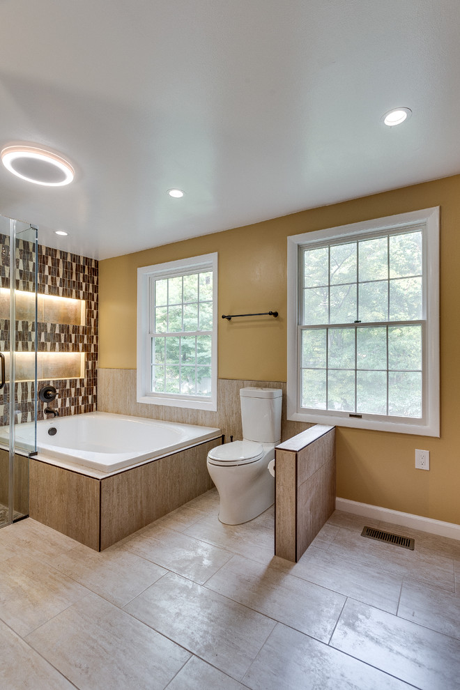 Photo of a large traditional master bathroom in DC Metro with raised-panel cabinets, medium wood cabinets, a corner tub, a corner shower, a two-piece toilet, beige tile, brown tile, ceramic tile, beige walls, bamboo floors, an undermount sink and granite benchtops.