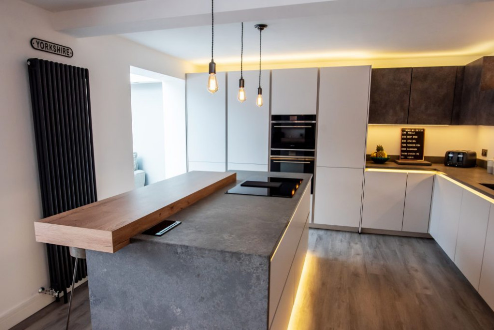 Photo of a large modern grey and white enclosed kitchen with grey cabinets, concrete worktops, white splashback, an island, grey worktops and feature lighting.