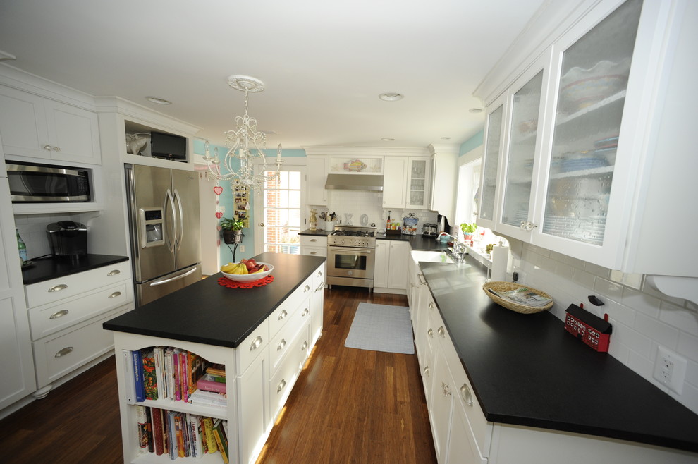 Inspiration for a large transitional u-shaped medium tone wood floor enclosed kitchen remodel in Baltimore with a farmhouse sink, glass-front cabinets, white cabinets, soapstone countertops, white backsplash, subway tile backsplash, stainless steel appliances and an island