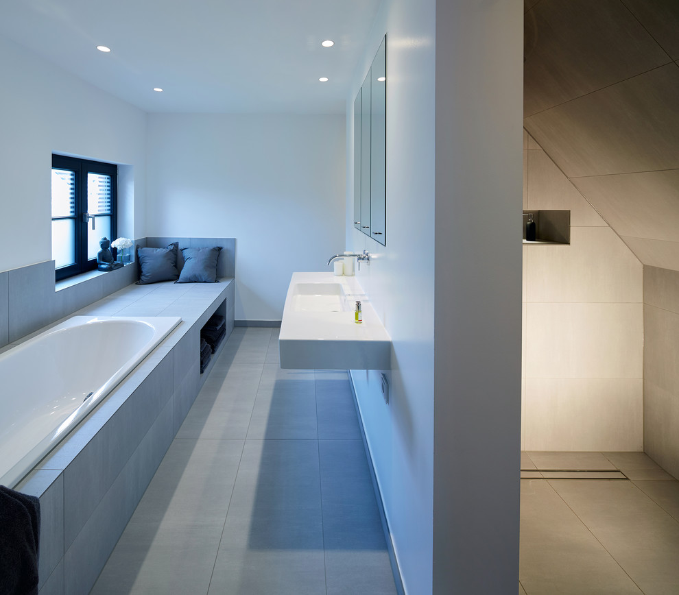 This is an example of a mid-sized contemporary master bathroom in Cologne with a drop-in tub, gray tile, cement tile, white walls, cement tiles, a wall-mount sink, grey floor, a curbless shower and an open shower.