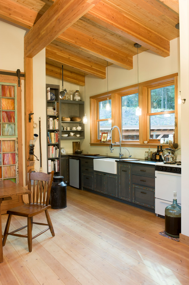 Inspiration for a small country u-shaped kitchen in Seattle with a farmhouse sink, shaker cabinets, grey cabinets, solid surface benchtops, light hardwood floors, no island and white appliances.