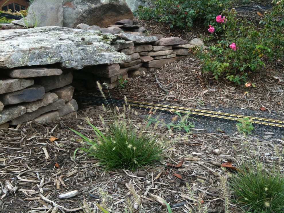 This is an example of a large rustic partial sun backyard stone formal garden for summer.