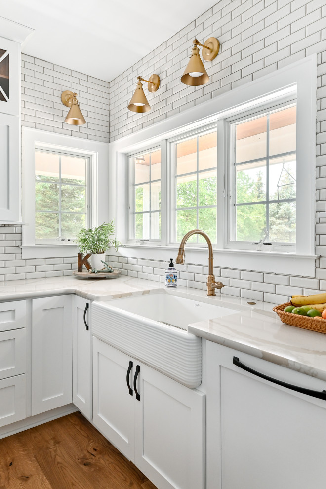 Design ideas for an expansive transitional u-shaped eat-in kitchen in Milwaukee with a farmhouse sink, shaker cabinets, blue cabinets, quartzite benchtops, white splashback, subway tile splashback, panelled appliances, vinyl floors, with island, brown floor and white benchtop.