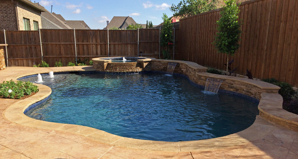 Photo of a large backyard custom-shaped natural pool in Dallas with a hot tub and natural stone pavers.