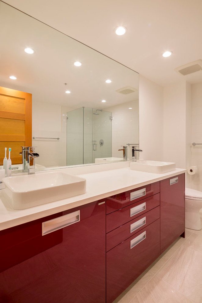 Photo of a mid-sized modern master bathroom in Vancouver with a vessel sink, red cabinets, engineered quartz benchtops, a drop-in tub, a corner shower, a one-piece toilet, gray tile, porcelain tile, white walls, flat-panel cabinets, laminate floors, grey floor and a hinged shower door.