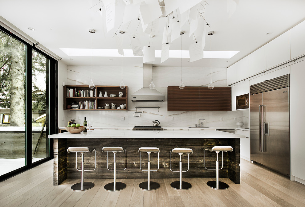 Inspiration for a modern l-shaped kitchen in Toronto with with island, a double-bowl sink, flat-panel cabinets, medium wood cabinets, marble benchtops, white splashback, stainless steel appliances and light hardwood floors.