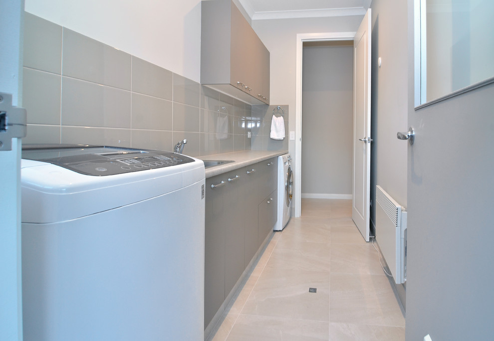 This is an example of a small contemporary single-wall dedicated laundry room in Sydney with a single-bowl sink, grey cabinets, laminate benchtops, beige walls and ceramic floors.