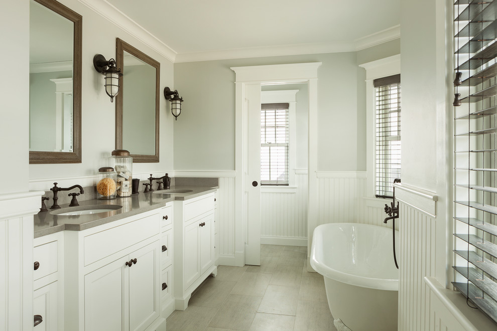 Beach style bathroom in Portland Maine with recessed-panel cabinets, white cabinets, a claw-foot tub, grey walls, an undermount sink, grey floor and grey benchtops.