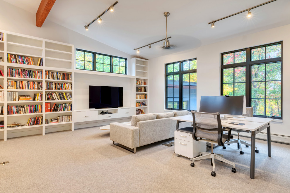 ニューヨークにあるコンテンポラリースタイルのおしゃれなホームオフィス・書斎 (ライブラリー、白い壁、カーペット敷き、暖炉なし、自立型机、グレーの床、三角天井) の写真