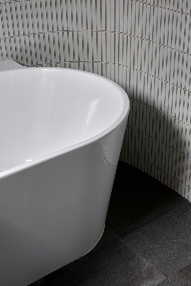 Design ideas for a medium sized contemporary ensuite bathroom in Melbourne with flat-panel cabinets, grey cabinets, a freestanding bath, a walk-in shower, a wall mounted toilet, multi-coloured tiles, porcelain tiles, multi-coloured walls, porcelain flooring, a vessel sink, tiled worktops, grey floors, an open shower, grey worktops, a single sink, a built in vanity unit and a vaulted ceiling.