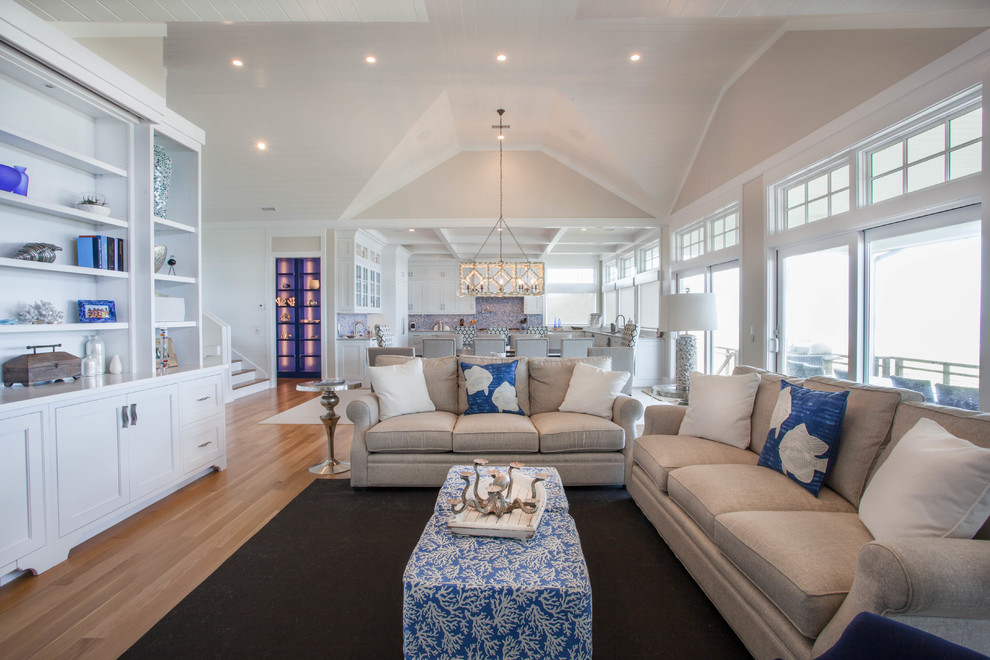 Photo of a mid-sized beach style open concept living room in Other with beige walls, light hardwood floors, a standard fireplace, no tv, a brick fireplace surround and brown floor.