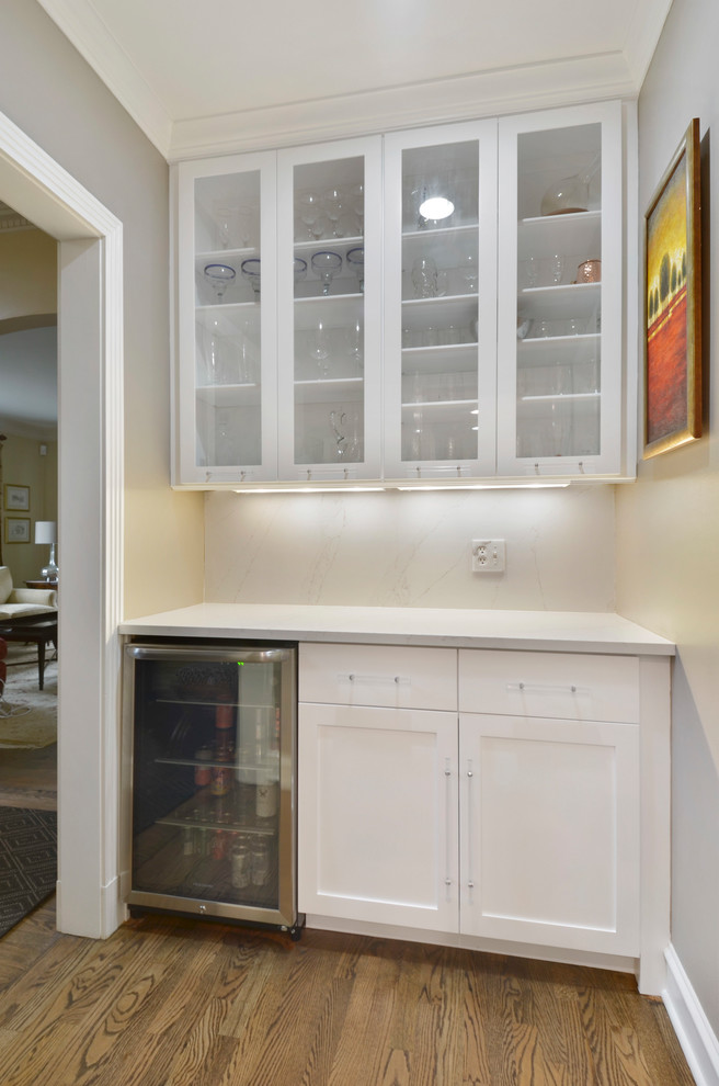 Example of a mid-sized transitional single-wall medium tone wood floor open concept kitchen design in Chicago with an undermount sink, shaker cabinets, white cabinets, quartz countertops, gray backsplash, ceramic backsplash, stainless steel appliances, an island and white countertops
