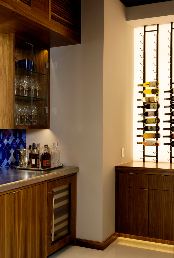 Photo of a mid-sized contemporary l-shaped wet bar in Houston with flat-panel cabinets, medium wood cabinets, stainless steel benchtops, blue splashback, porcelain splashback and porcelain floors.