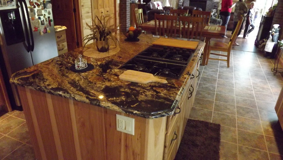 Example of a mountain style u-shaped porcelain tile and brown floor enclosed kitchen design with an undermount sink, stainless steel appliances and an island