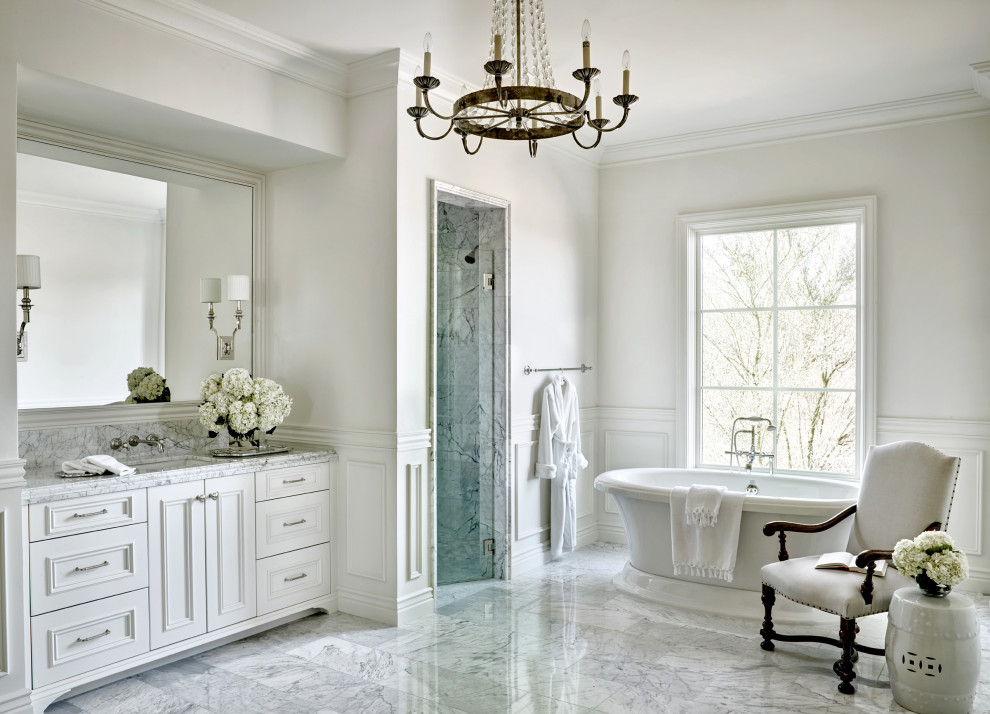 This is an example of a traditional bathroom in Phoenix with recessed-panel cabinets, white cabinets, a freestanding tub, an alcove shower, gray tile, white walls, an undermount sink, grey floor, a hinged shower door, grey benchtops, a single vanity, a built-in vanity and decorative wall panelling.