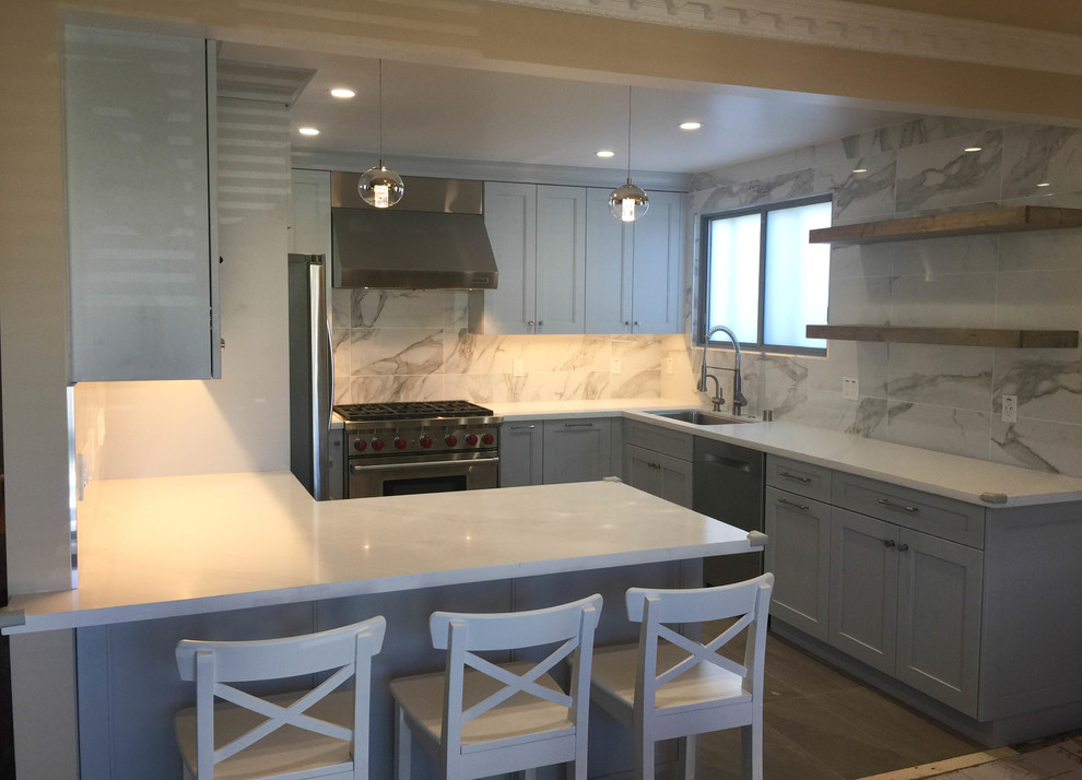 Example of a mid-sized transitional u-shaped porcelain tile and gray floor eat-in kitchen design in San Francisco with an undermount sink, recessed-panel cabinets, gray cabinets, quartz countertops, gray backsplash, porcelain backsplash, stainless steel appliances and white countertops