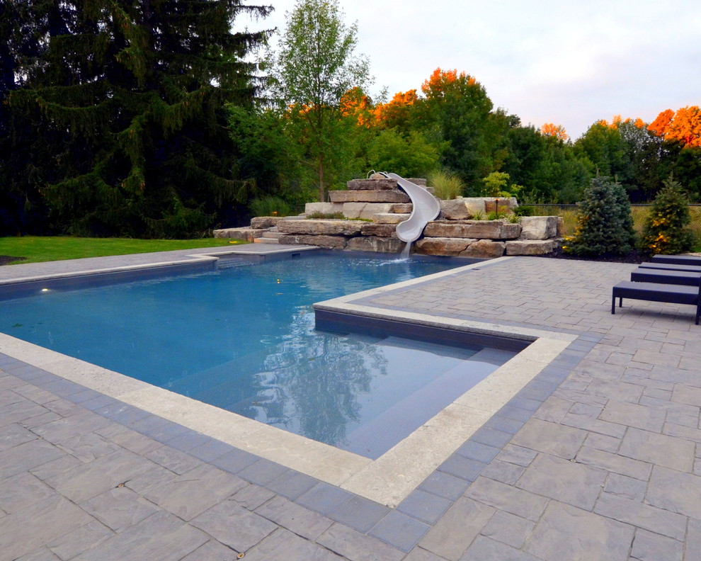 Inspiration for a contemporary backyard l-shaped pool in Toronto with a water slide and concrete pavers.