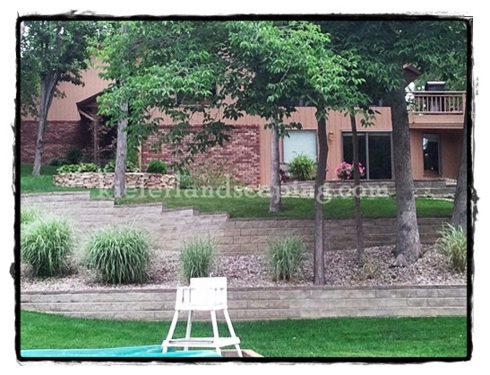 Design ideas for a mid-sized contemporary sloped garden in Chicago with a retaining wall and natural stone pavers.