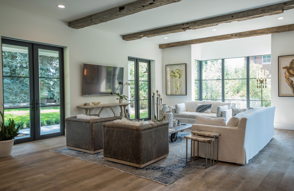 Foto di un soggiorno country aperto con sala formale, pareti bianche, pavimento in legno massello medio, TV a parete, pavimento grigio e travi a vista