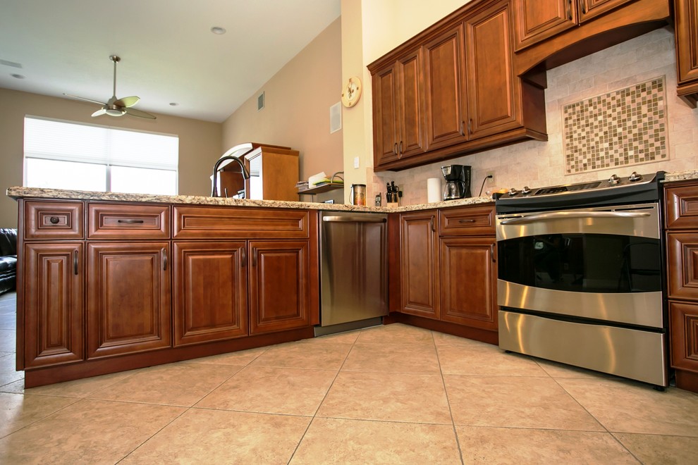 Mid-sized transitional u-shaped porcelain tile eat-in kitchen photo in Miami with an undermount sink, raised-panel cabinets, brown cabinets, granite countertops, beige backsplash, stone tile backsplash, stainless steel appliances, beige walls and a peninsula