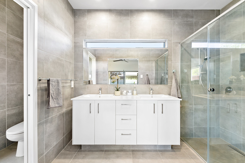 Inspiration for a contemporary master bathroom in Sunshine Coast with flat-panel cabinets, white cabinets, a curbless shower, gray tile, grey walls, grey floor and white benchtops.