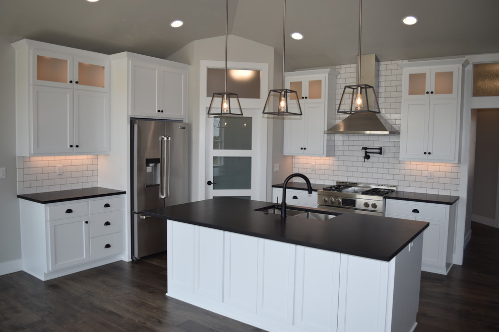 Inspiration for a large l-shaped dark wood floor and brown floor open concept kitchen remodel with an undermount sink, recessed-panel cabinets, white cabinets, granite countertops, white backsplash, ceramic backsplash, stainless steel appliances and an island
